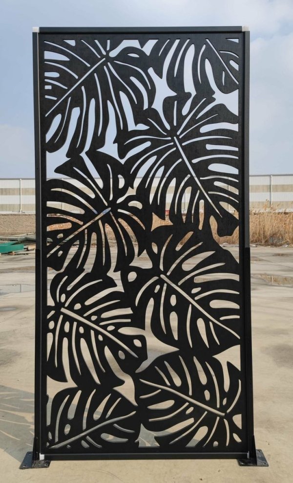 Heavy-duty black powder-coated metal partition screen featuring a precision laser-cut Monstera leaf pattern, manufactured by Faisal Laser Works.