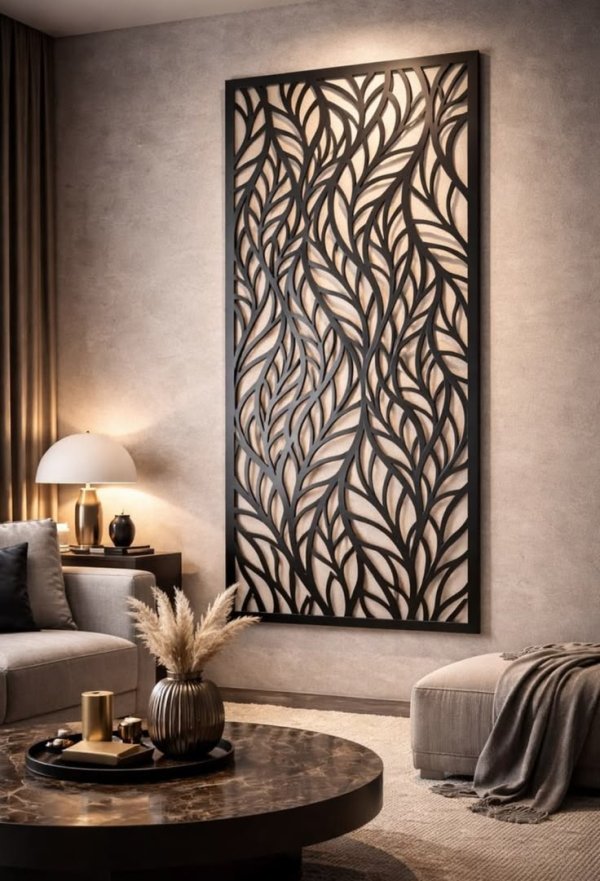 Large rectangular matte black CNC laser cut metal wall art featuring an interconnected organic leaf and vine pattern with warm LED backlighting, mounted on a modern living room wall by Faisal Laser Works.